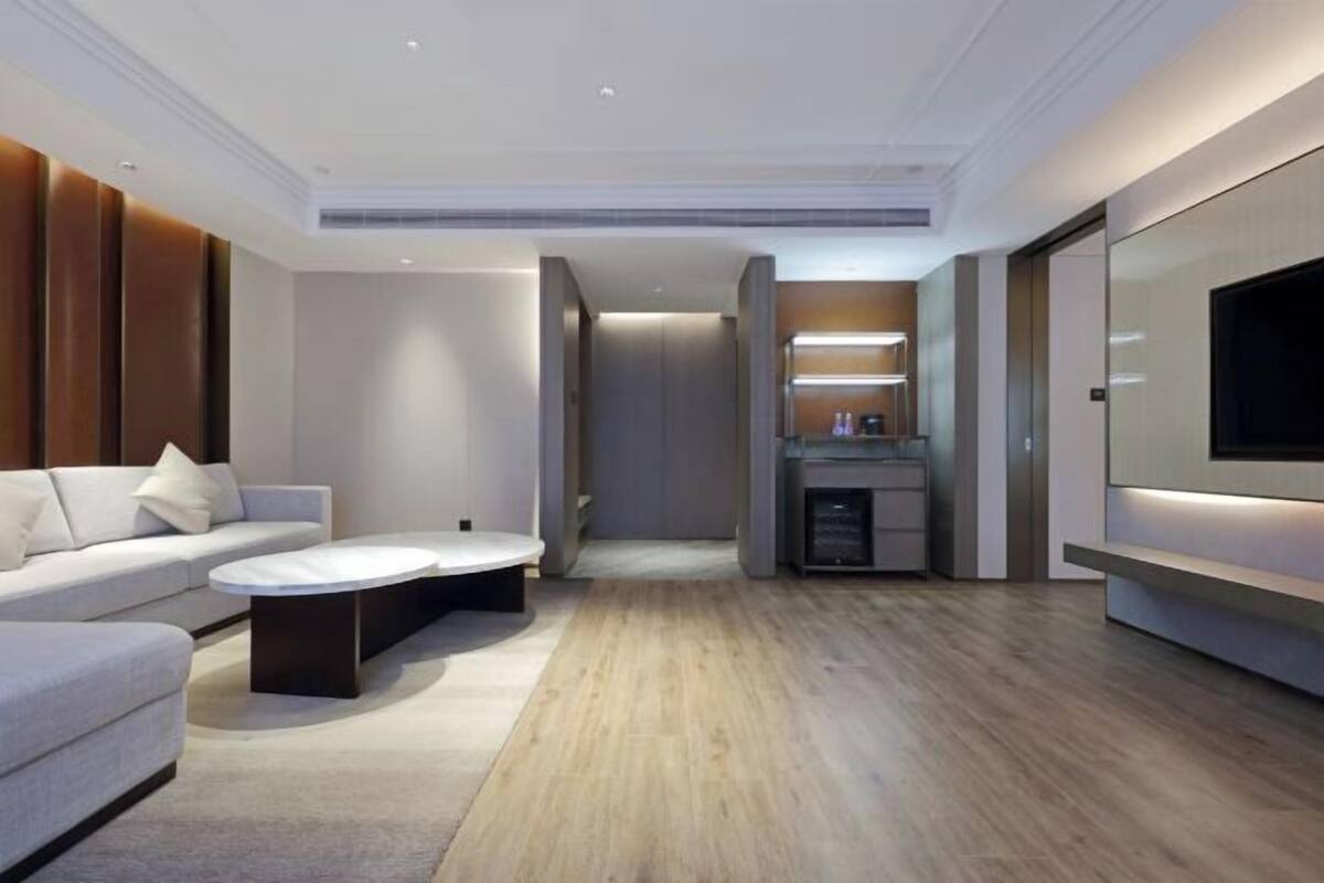 A modern living room with a sofa, coffee table, and a TV mounted on the wall.
