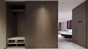 A modern hotel corridor with a bench, a large wooden panel, and a seating area with a sofa and a coffee table.