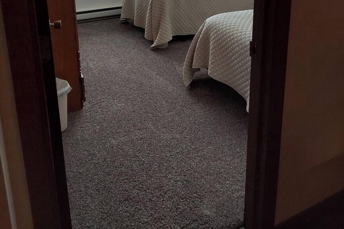 A hotel room with two beds, a large window, and a ceiling fan.