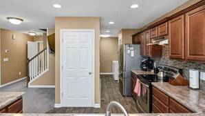 A modern kitchen with wooden cabinets, a stainless steel refrigerator, and a granite countertop. - Spacious Split-Level Retreat | Sleeps 11 (Saluda County)