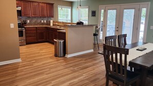 A spacious kitchen with wooden cabinets, a granite countertop, and a central island. - Spacious Split-Level Retreat | Sleeps 11 (Saluda County)
