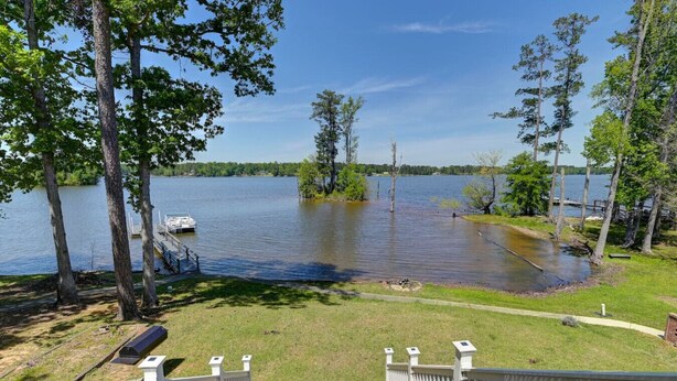 A lakeside property with a dock, a wooden deck, and a white fence. - Spacious Split-Level Retreat | Sleeps 11 (Saluda County)