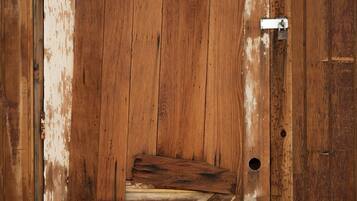 A rustic wooden door with a metal latch and a cross-patterned floor design.