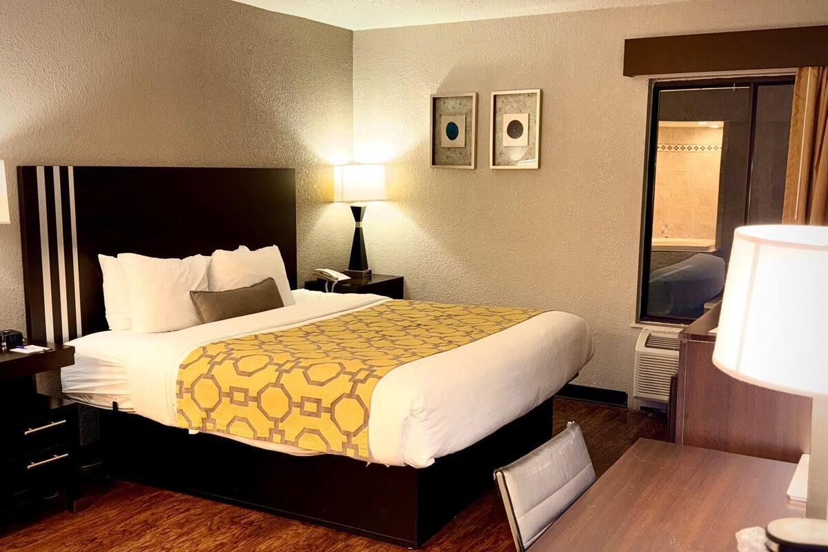 A hotel room with a bed, bedside tables, a desk, and a chair.