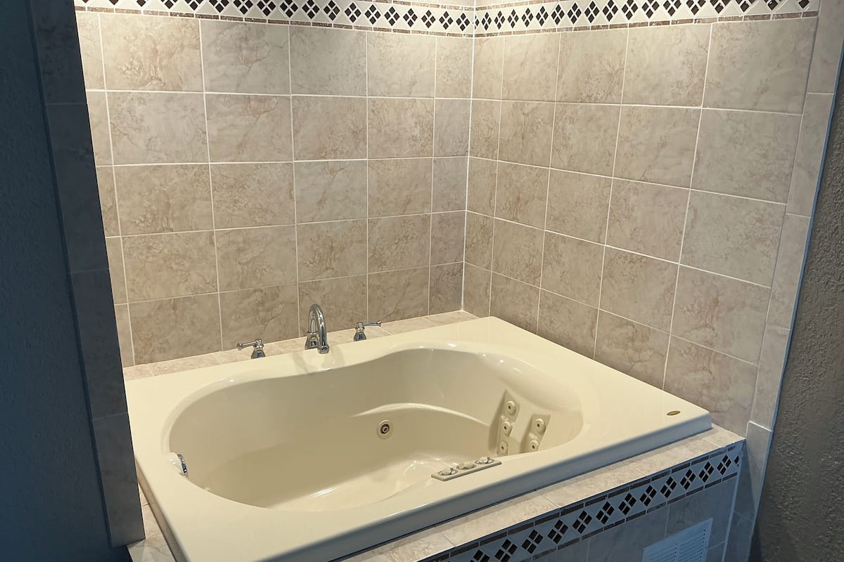 A bathroom with a freestanding bathtub, tiled walls, and a decorative border.