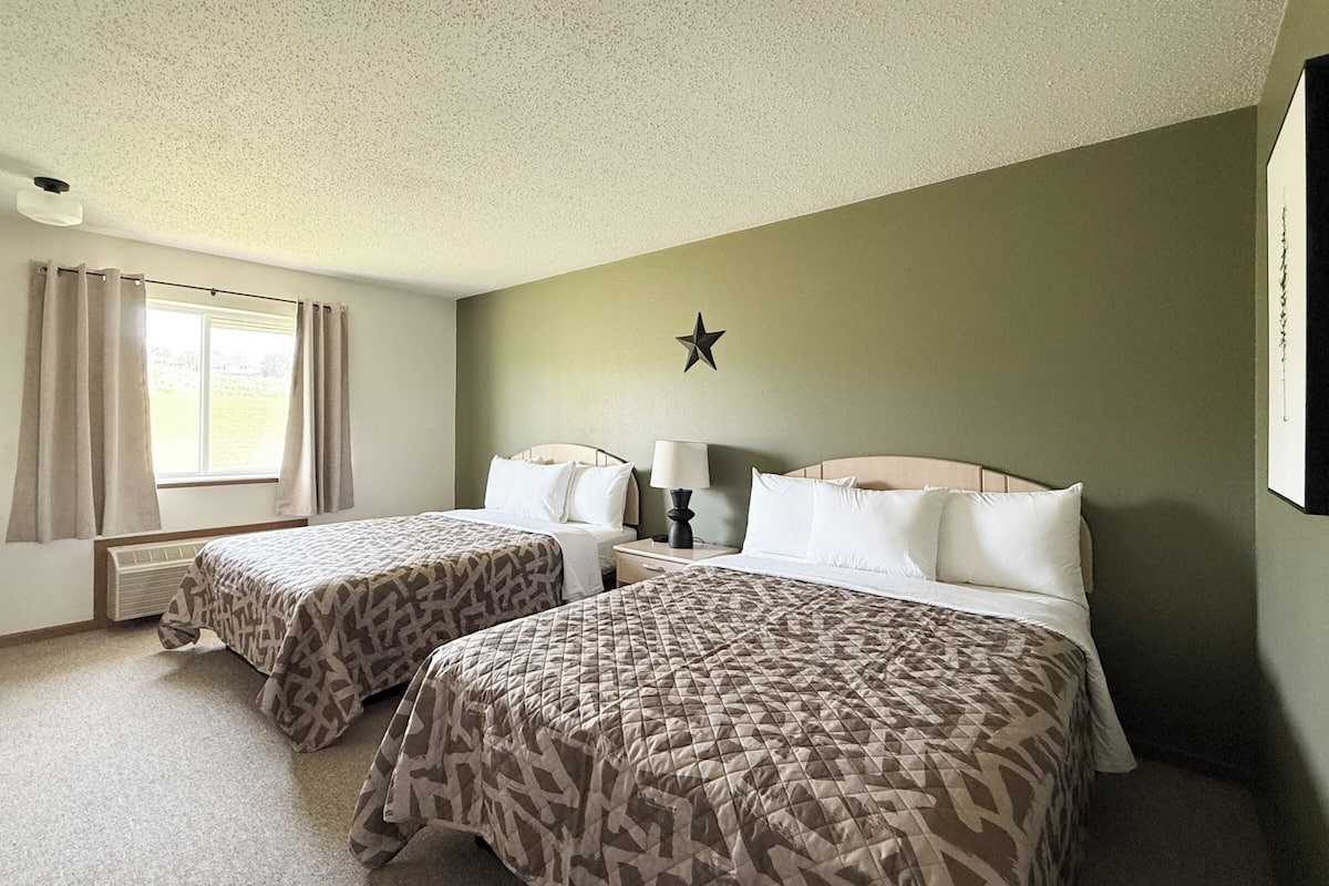 A hotel room with two beds, a star decoration on the wall, and a window with curtains.