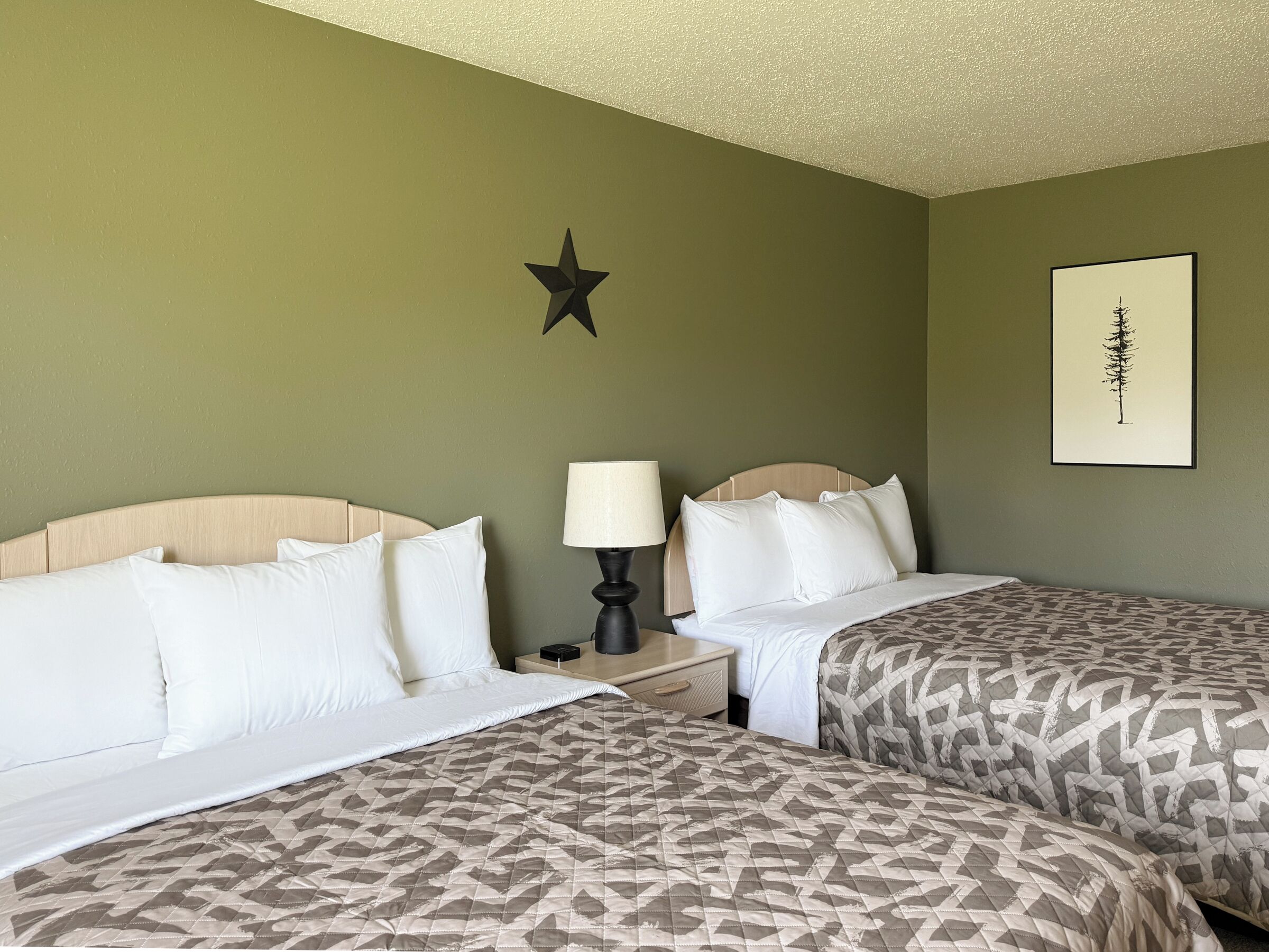 Une chambre d’hôtel avec deux lits, une décoration en forme d’étoile au mur et un tableau encadré.