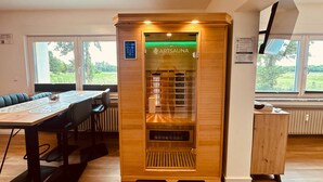 Una sauna con pannello di controllo, rivestimento in legno e vista all'esterno tramite ampie finestre.