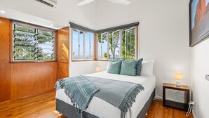 Un dormitorio con una cama grande, dos mesitas de noche y una ventana con vistas a árboles.