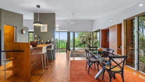 Una cocina moderna con barra, ventanas amplias y un comedor con alfombra roja.
