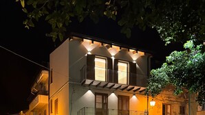 Un edificio a due piani con un balcone al secondo piano, un ingresso al piano terra e una strada di fronte.