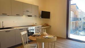 Una cucina moderna con zona pranzo, una TV montata sopra il bancone e un'ampia finestra con vista sulla città.