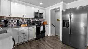 A modern kitchen with white cabinets, a stainless steel refrigerator, a microwave, and a coffee maker. - LAMBEAUView|7 MinWalk|Sleeps10 (Green Bay)