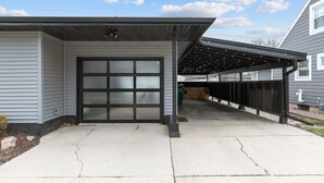 A garage with a large glass door, a covered patio area, and a concrete driveway. - LAMBEAUView|7 MinWalk|Sleeps10 (Green Bay)