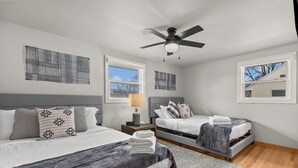 A bedroom with two beds, a ceiling fan, and artwork on the walls. - LAMBEAUView|7 MinWalk|Sleeps10 (Green Bay)