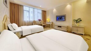 Una habitación de hotel con dos camas, un escritorio, un televisor y un mueble pequeño.