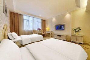 Ein Hotelzimmer mit zwei Betten, einem Schreibtisch, einem Fernseher und einer kleinen Kommode.