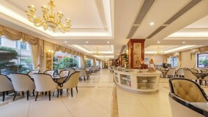 Un comedor de hotel con varias mesas y sillas, una barra central y candelabros.