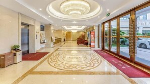 Un vestíbulo de hotel con piso de mármol, una recepción y un amplio ventanal con vista a la calle.