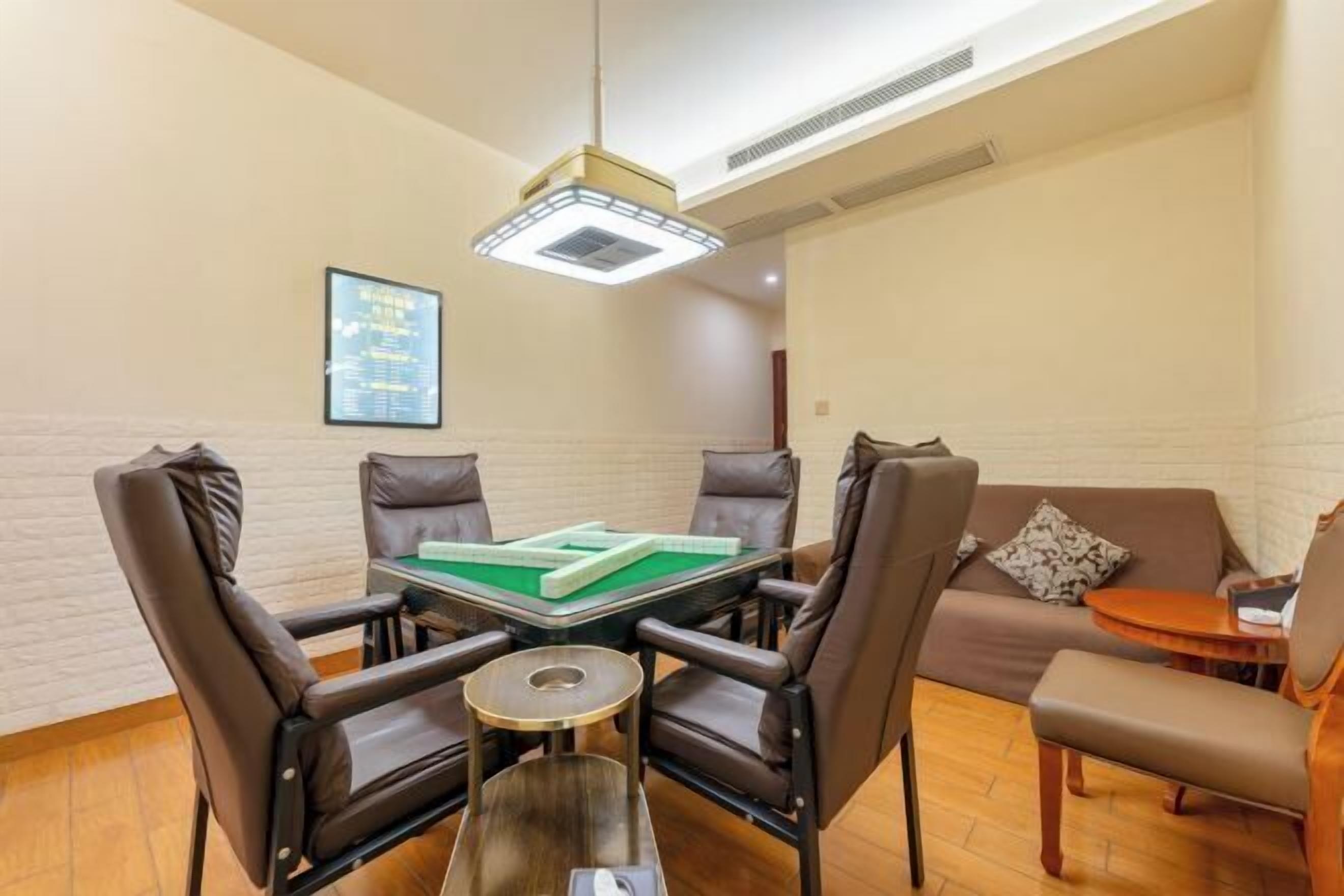 Una habitación con mesa de billar, cuatro sillas, un sofá, una pequeña mesa redonda y una lámpara colgante.
