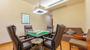 Una habitación con mesa de billar, cuatro sillas, un sofá, una pequeña mesa redonda y una lámpara colgante.
