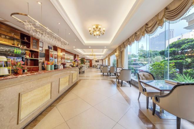 A hotel lobby with a reception desk, seating area, and large windows offering a view of the outdoors.