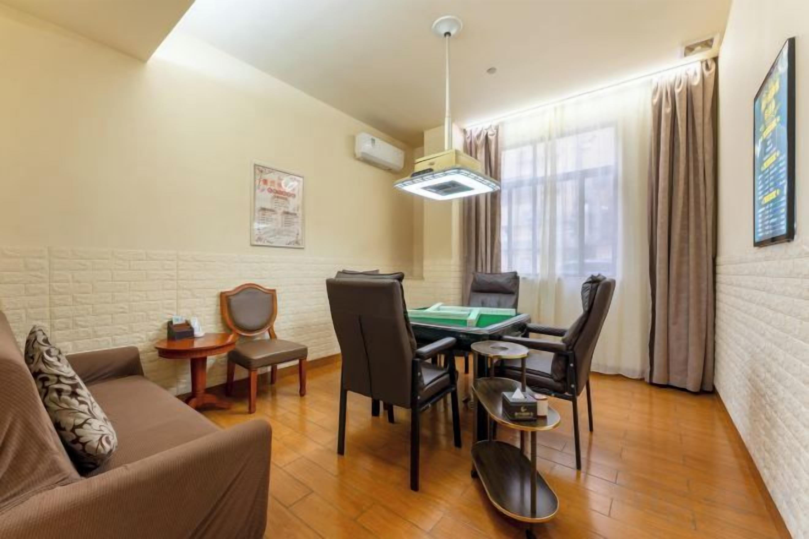 Uma sala de estar com sofá, mesa de jantar e cadeiras, mesa de bilhar e luminária no teto.
