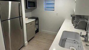 Eine kleine Küche mit einem Edelstahlkühlschrank, einer Mikrowelle und einem Waschbecken.
