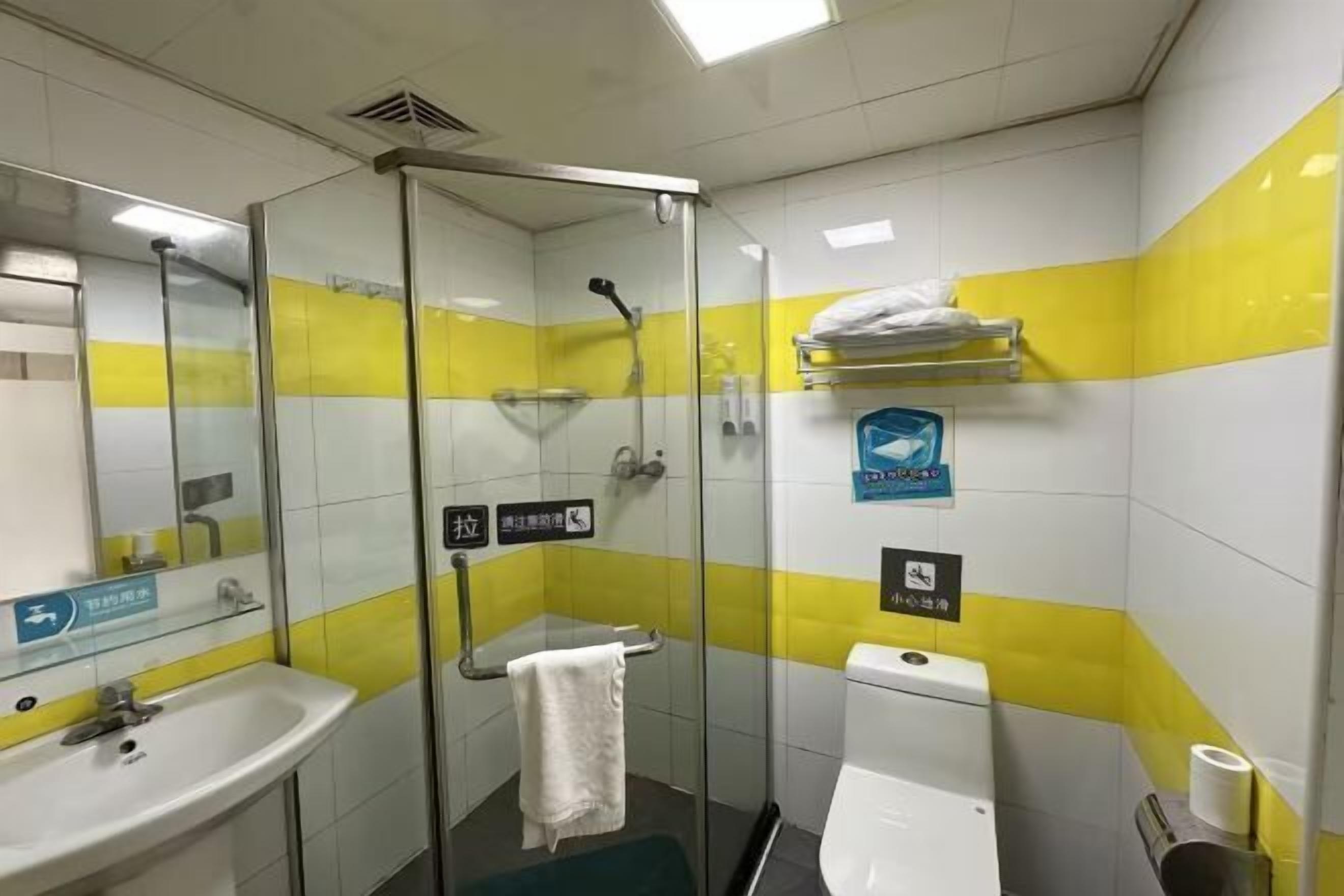 Un baño con cabina de ducha de vidrio, un lavabo, un inodoro y un perchero para toallas.