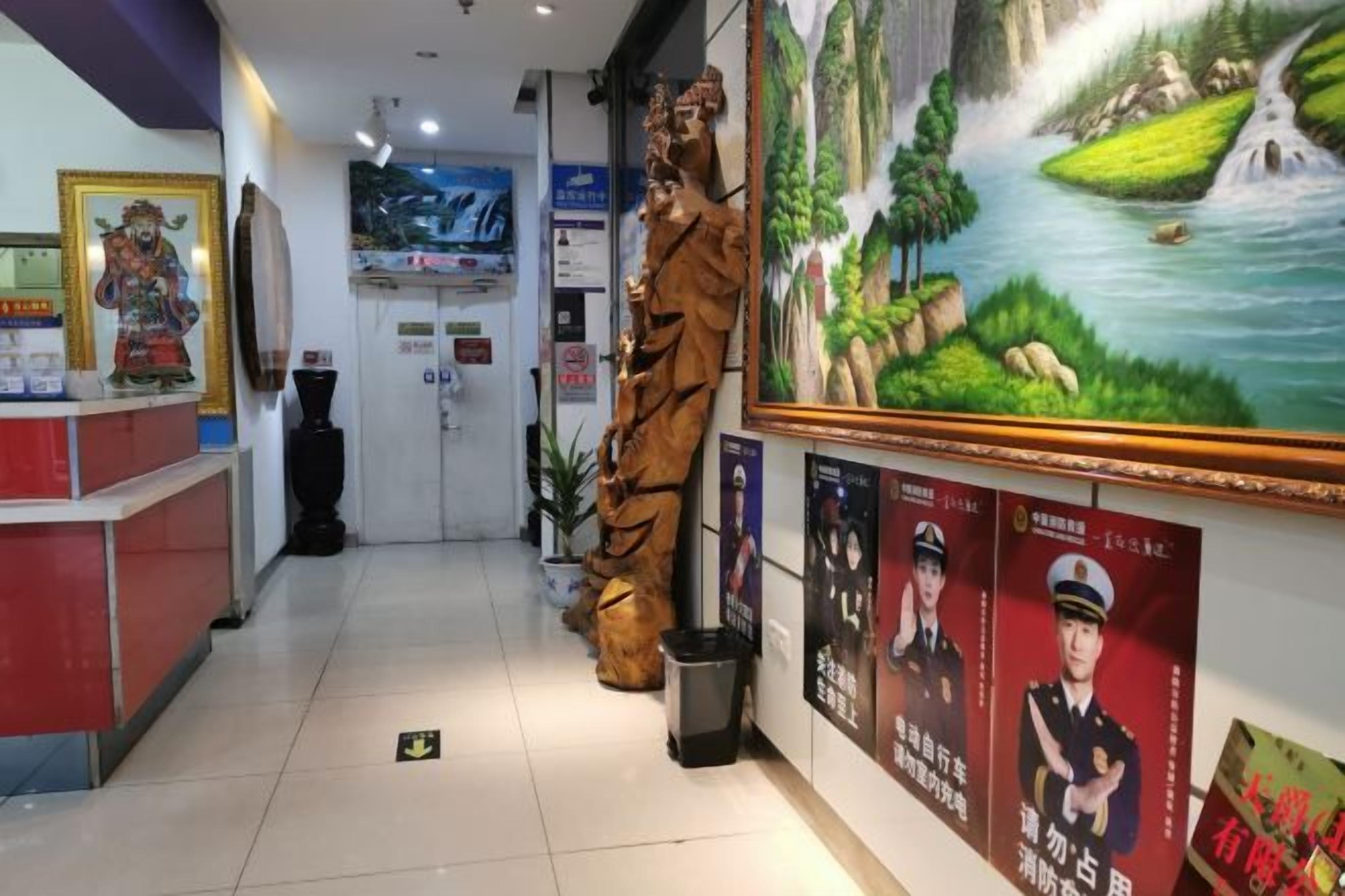 Una zona d'entrada amb una taquilla de recepció, una gran estàtua, un quadre de paisatge i diversos cartells.