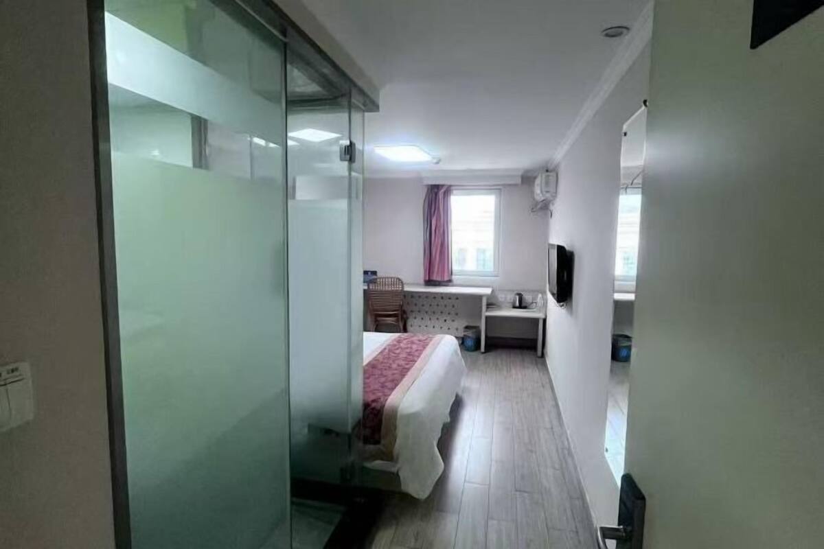 A hotel room with a bed, a desk, a chair, a television, and a window with curtains.