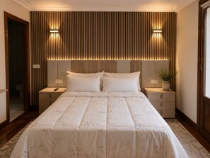 A hotel room with a large bed, two bedside tables, a nightstand, a wall-mounted light fixture, and a potted plant. - Matzuri Nekazal Turismoa (Mutriku)