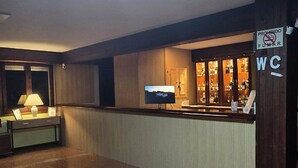 Un vestíbulo espacioso con piso de granito pulido, una mesa de recepción, un televisor de pantalla plana grande y un letrero que indica prohibido fumar.