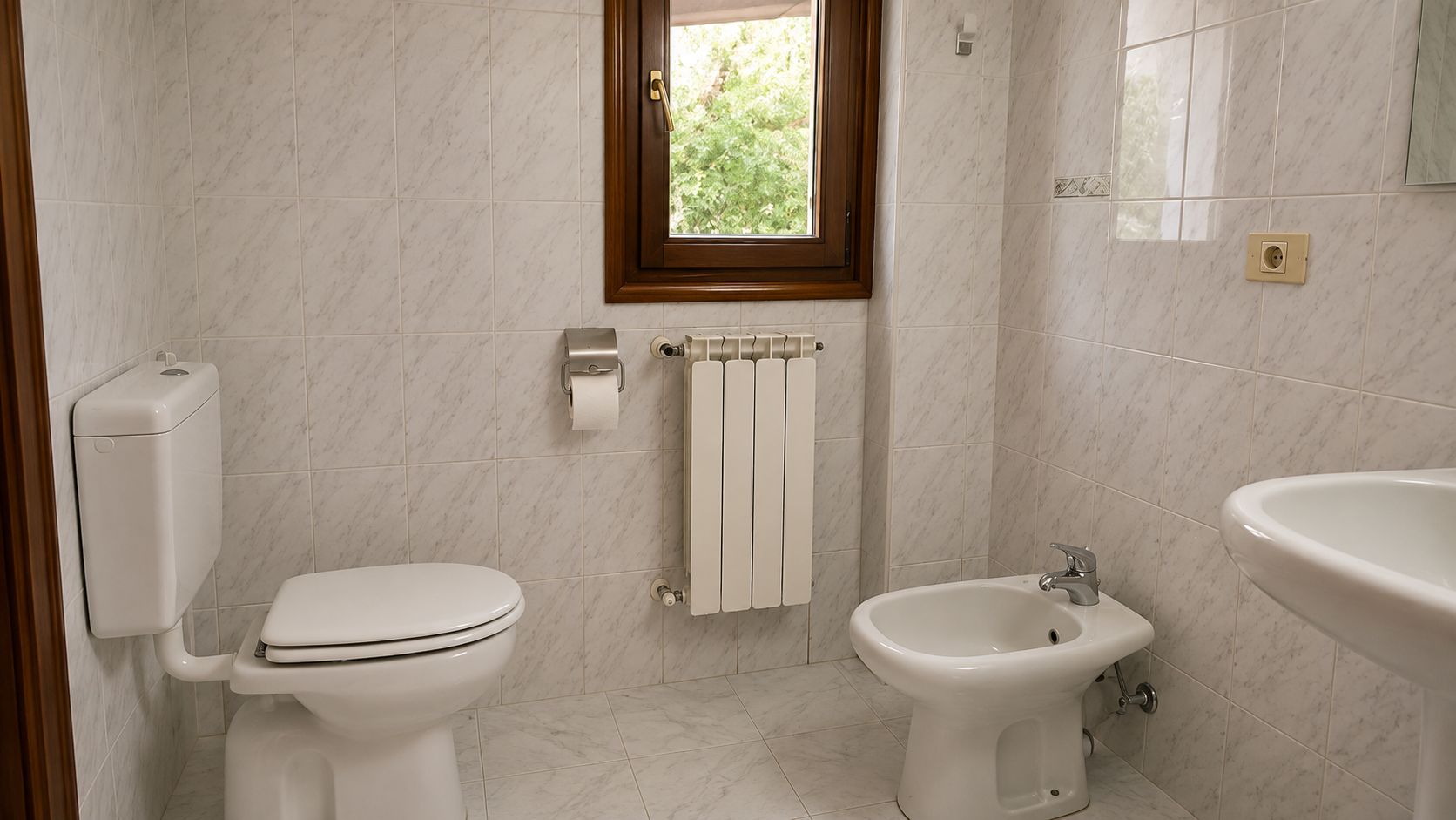 Ein Badezimmer mit Toilette, Bidet und Waschbecken, alles in Weiß.