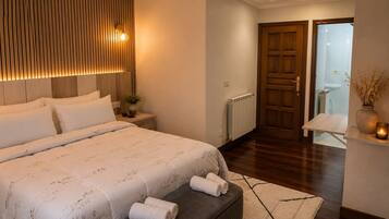 A bedroom with a bed, bedside table, and a view of a bathroom through an open door.