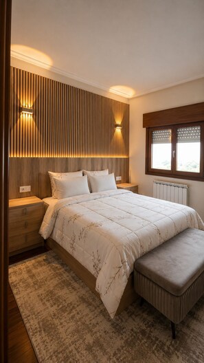 Une chambre à coucher avec un grand lit, une table de chevet, un banc, une lampe fixée au mur et une fenêtre avec des stores.