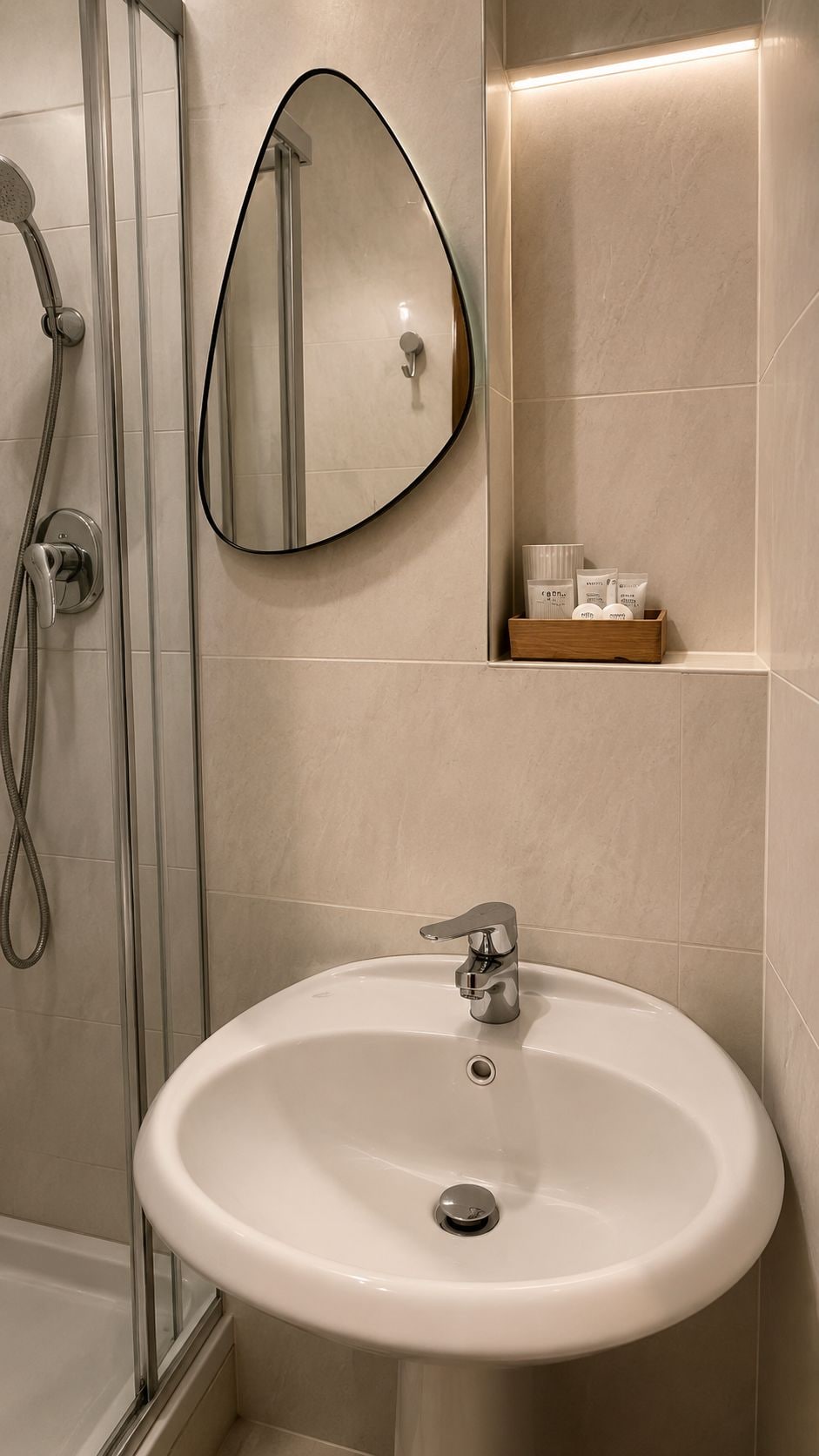 Une salle de bain avec un lavabo blanc, une douche avec une porte en verre et un miroir.