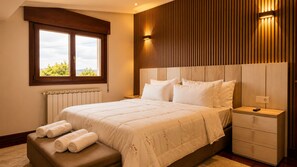Un dormitorio con una cama grande, cabecera de madera, una mesita de noche y ventana con vistas.