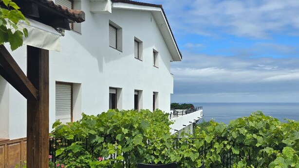 Un edificio blanco con varias ventanas y un balcón con vista al agua.