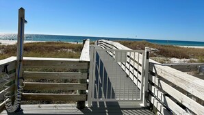 A wooden boardwalk leading to a beach with a clear blue sky.