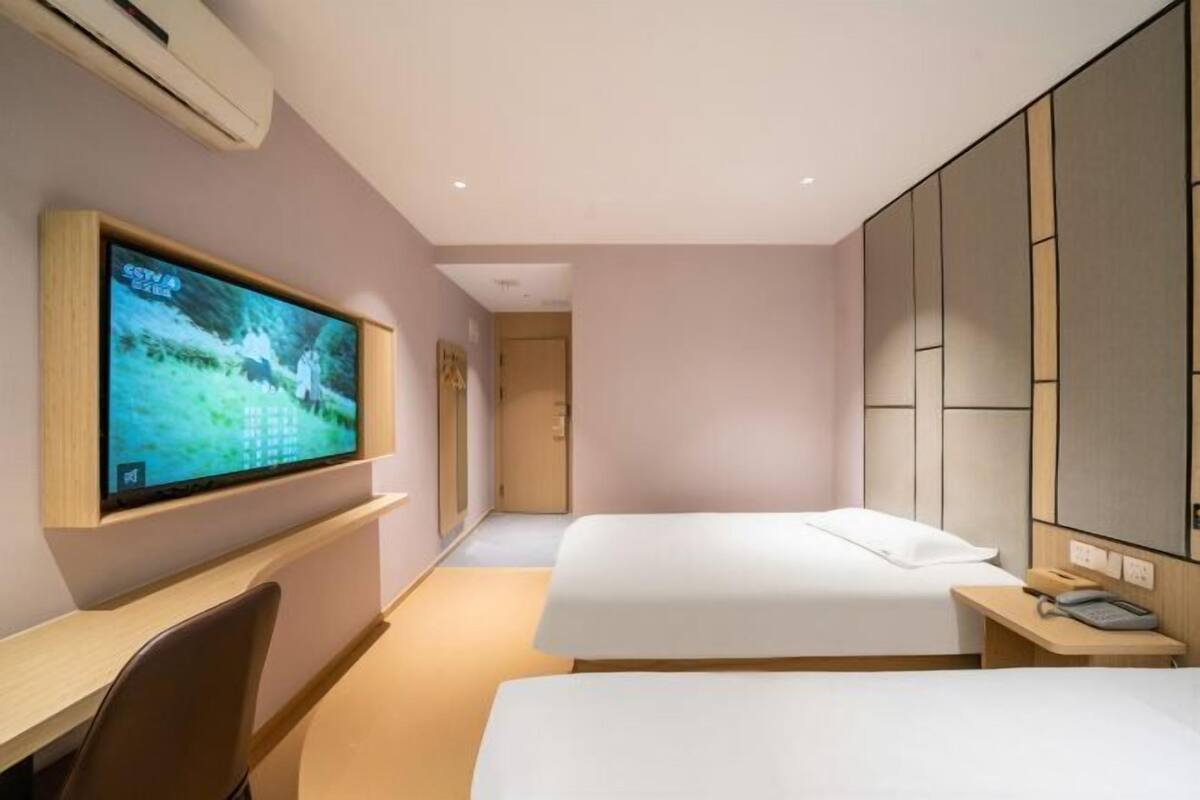 A hotel room with a TV, two beds, a desk, and a phone.