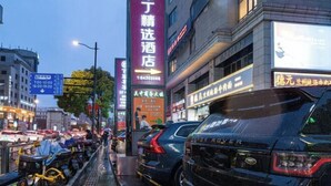 A busy urban street with a prominent hotel sign, multiple vehicles, and commercial buildings. - Enjoy Hotel (Wuzhong Road) (Shanghai)