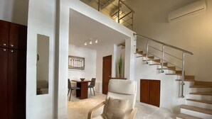 Amplia sala de estar con techo alto, una escalera y un comedor.