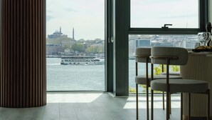 Una habitación moderna con un amplio ventanal que da a un río y al paisaje urbano.