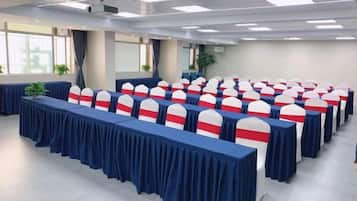 A conference room with rows of tables, chairs, and a projector on the ceiling.