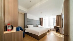 Ein Hotelzimmer mit zwei Betten, einem Schreibtisch und einem Stuhl.