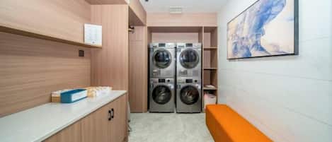 A laundry room with two washing machines, a bench, and a wall-mounted artwork.