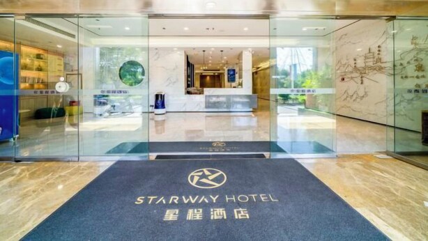 Der Eingang des Starway Hotels mit einer Rezeption, Glastüren und einem Marmorboden.