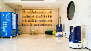 A hotel lobby with a vending machine, a bookshelf, and a coffee machine.