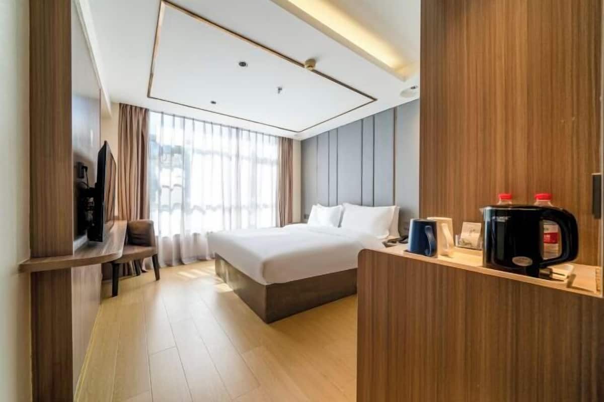 A hotel room with a bed, a TV, a coffee machine, and a desk.